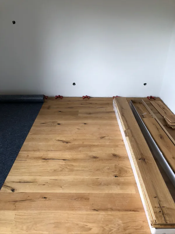 Dielenboden in der Verlegung: Trittschalldämmung unter den Dielen, Distanzkeile halten die Randfuge zur Wand frei